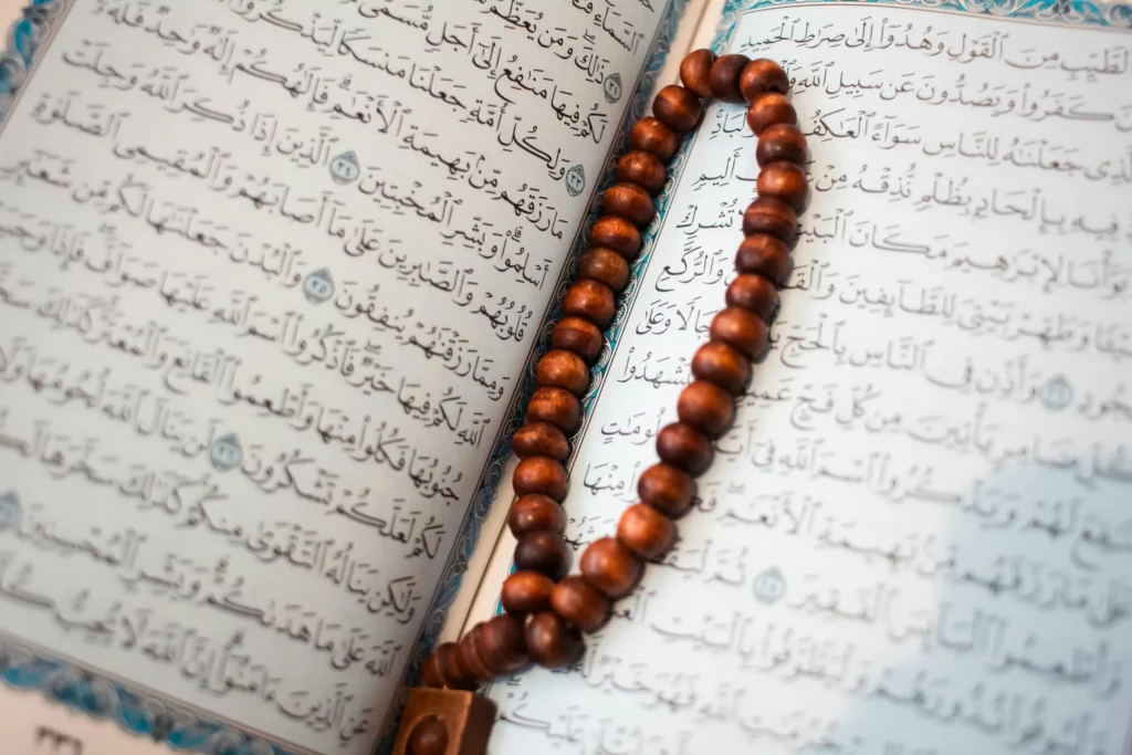 Chapelet en bois posé sur les pages ouvertes du Saint Coran écrit en arabe