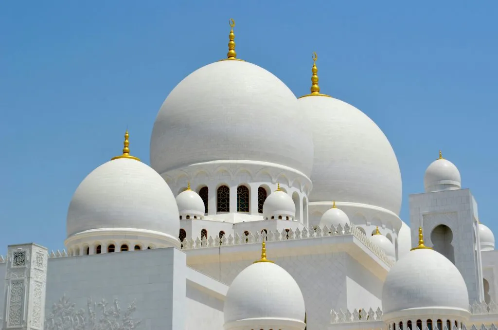 Gros plan sur les coupoles et dômes blancs ornés de croissants dorés d'une grande mosquée